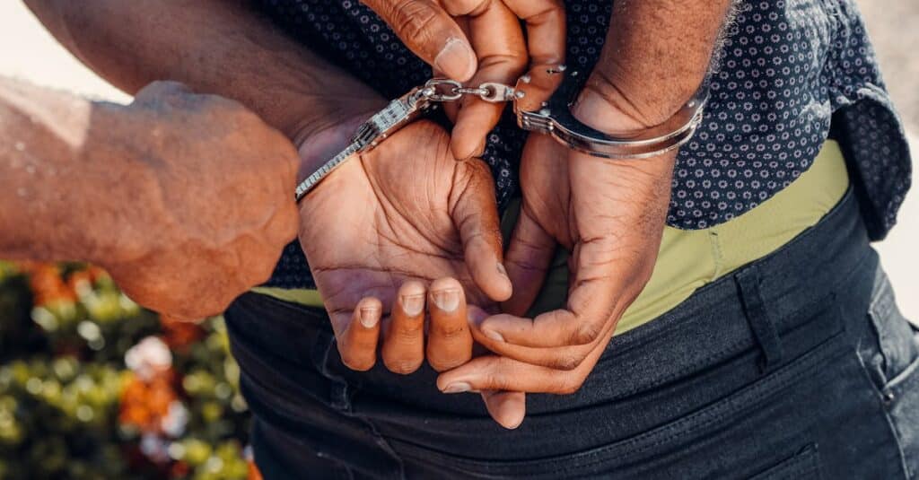 Close-up of a police officer handcuffing a man outdoors. Law enforcement in action.